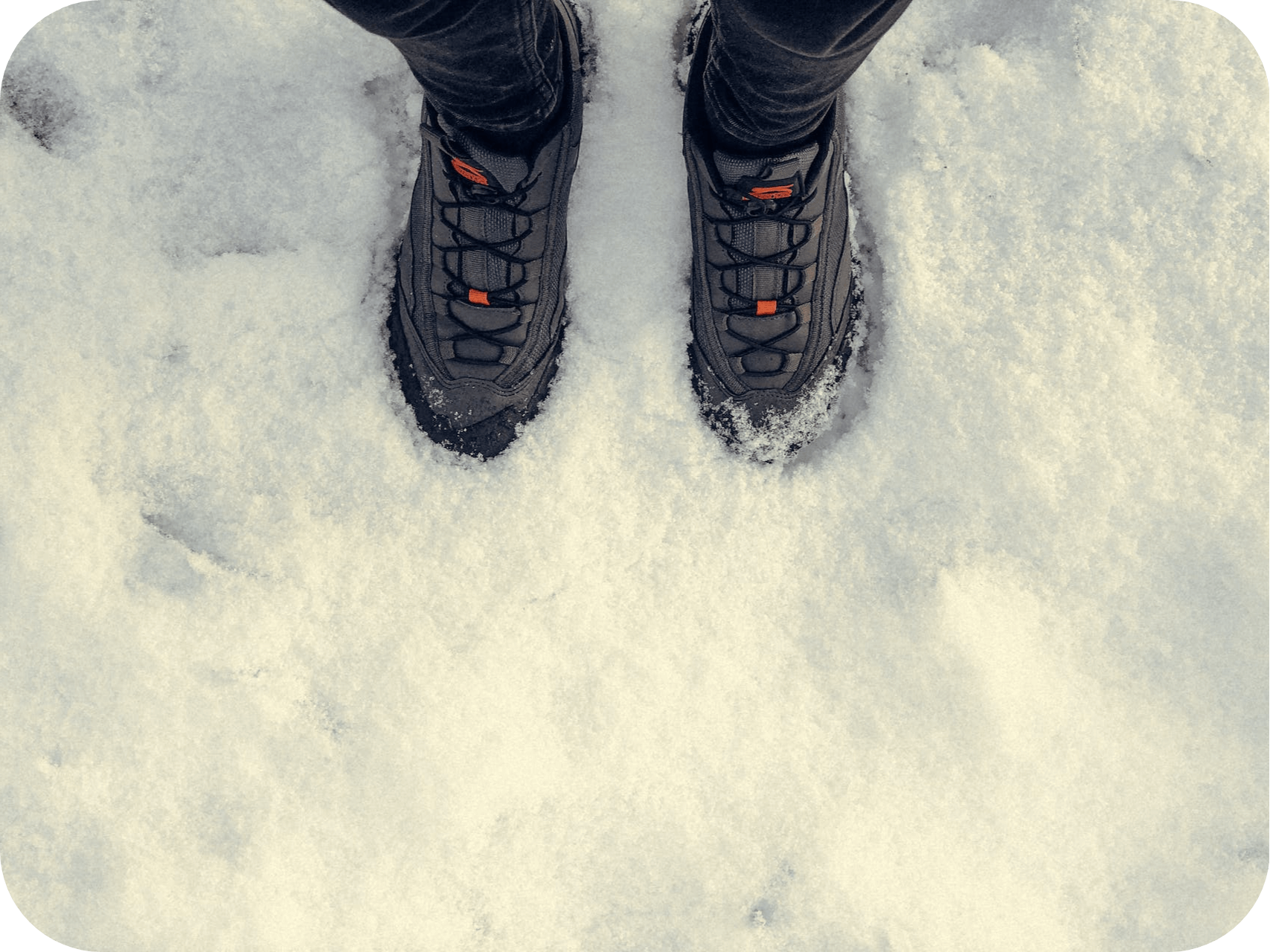 Pracovné úrazy. Zimná pracovná obuv zhora: Nohy v tepelne izolovanej a protišmykovej obuvi stojace na snehovej pokrývke. Ochrana a bezpečnosť v každom kroku počas zimného obdobia."